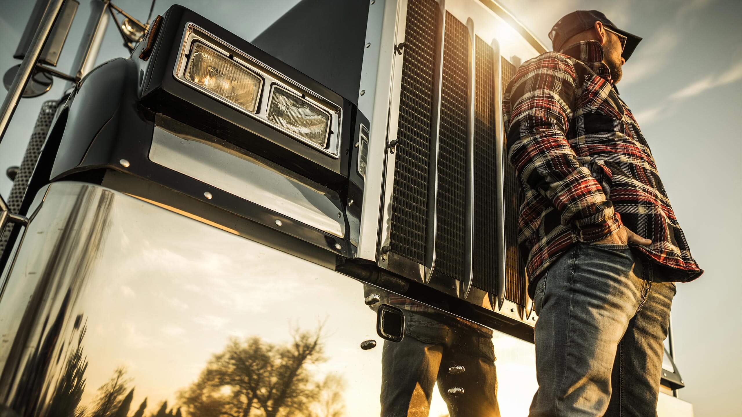Truck driver standing beside the grille of his rig